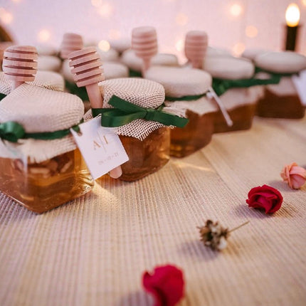 Jars of honey with decorative lids on a textured surface with flowers.