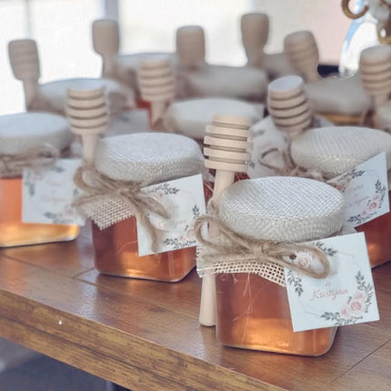 Jars of honey with wooden dipper sticks on a wooden surface